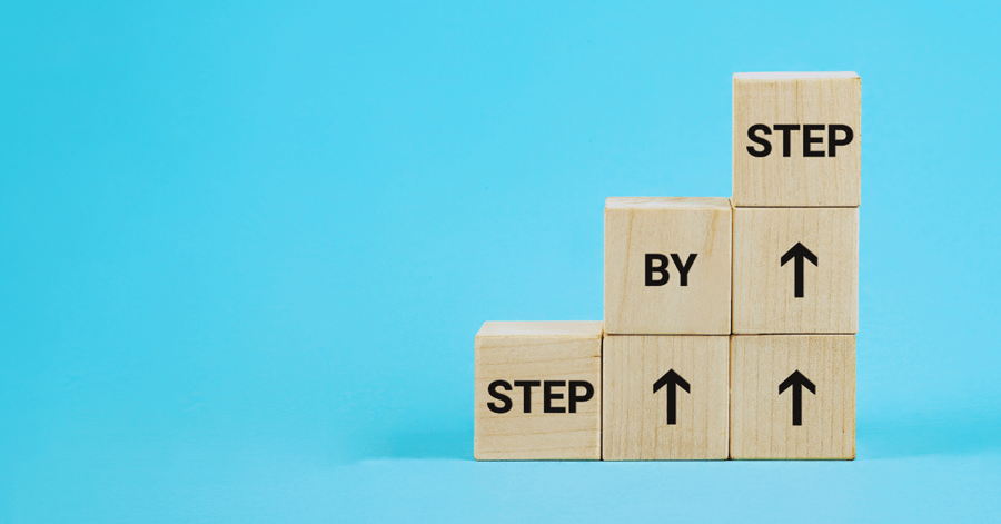 wooden blocks forming a stair saying 'step by step'